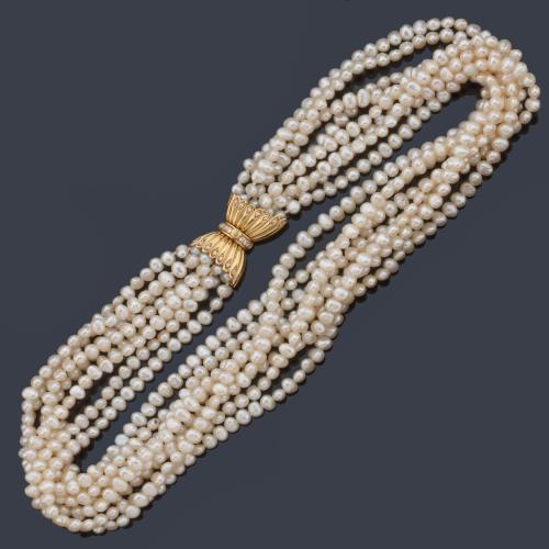  Collar con ocho hilos de perlas de rio en diferentes longitudes con cierre con diseño de lazada en oro amarillo de 18K.