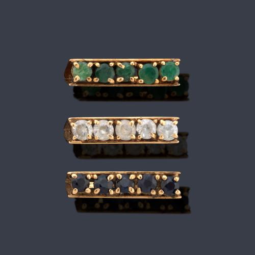  Tres anillos con banda de esmeraldas, zafiros y piedras incoloras en montura de oro amarillo de 18K.
