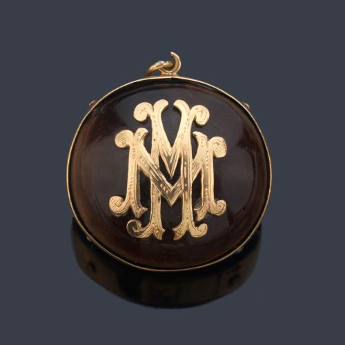 Colgante con diseño de semilla con doble 'M' en montura de oro amarillo de 18K.