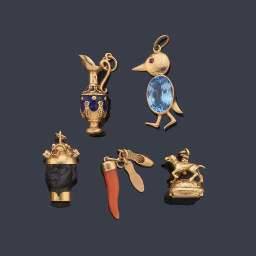 Lote con cinco dijes con diseño de anfora, pajarito, perro de caza, cabeza de moretto en madera y punta de coral en montura de oro amarillo de 18K.
