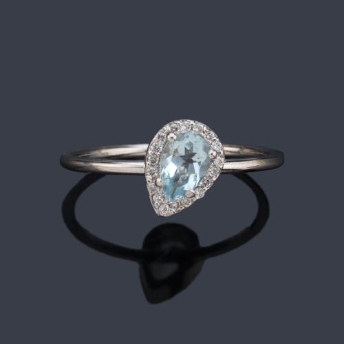  Anillo con aguamarina talla perilla y orla de brillantitos en montura de oro blanco de 18K.