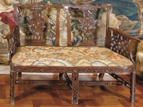 Banco o pequeño canapé Chippendale, época Jorge III, variante China—caracterizado por patrón geométrico, patas rectas caneladas en caoba tallada y calada al estilo oriental, de doble plaza de asiento. 