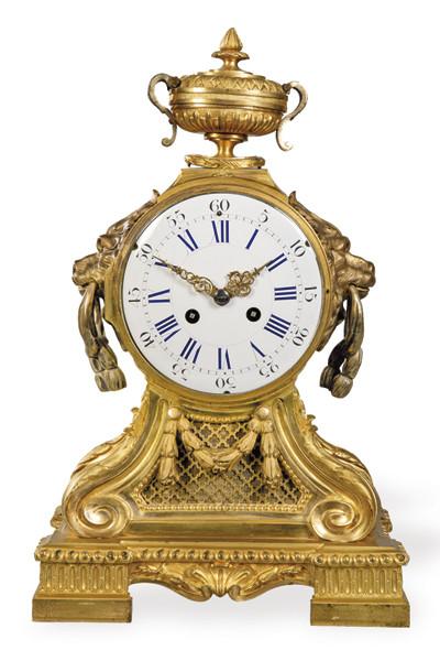 Reloj de sobremesa estilo Luis XVI, denominado también reloj de repisa, caracterizado por su cuerpo arquitectónico de bronce rematado por una urna en forma de copa,
