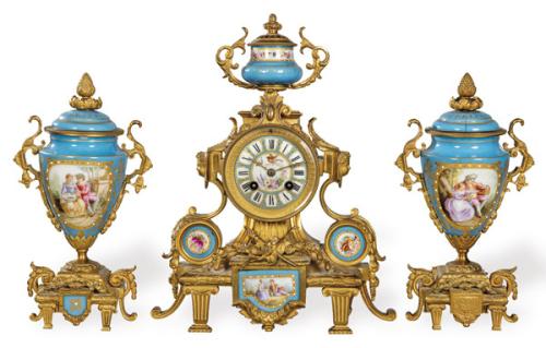  Reloj de sobremesa Napoleón III,  estilo Luis XVI, con guarnición de dos jarrones, en porcelana estilo Sèvres y bronce dorado.