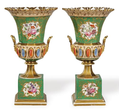 Pareja de urnas en forma de copa con reservas de flores sobre fondo verde y dorado, pequeñas asas modeladas y cabujones imitando piedras de colores.
