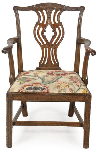 Silla con brazos Jorge III Chippendale, con respaldo calado y decoración tallada de motivos vegetales, brazos curvos, sobre patas rectas unidas por chambrana en H.