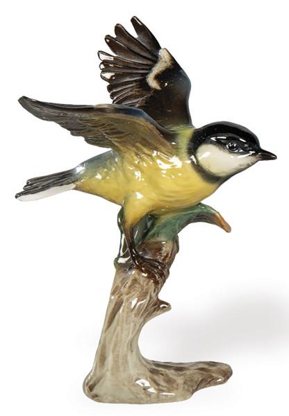  Figura de porcelana policromada representando un ave en vuelo, manufactura alemana Goebel, circa 1960–1970. Modelado naturalista de cuidada ejecución, con alas desplegadas y base en forma de tronco.