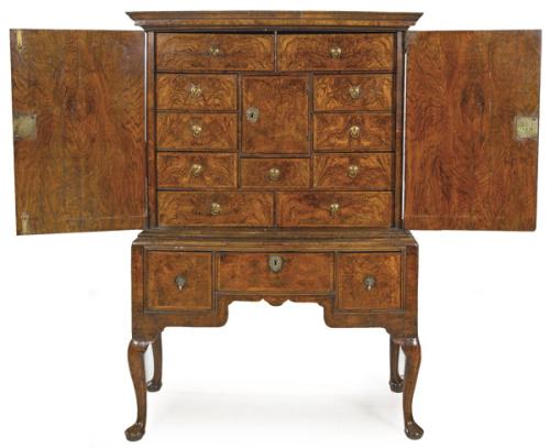  Cabinet Reina Ana, de dos cuerpos presenta un cuerpo superior rematado por con una cornisa rectangular moldeada con dos puertas de doble hoja que protegen un interior organizado en una puerta central que articula 11 cajones a su alrededor.