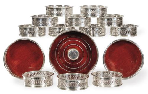 Tres reposa-botellas y doce posa-vasos de plata punzonada Ley Sterling, uno de ellos inglés y los otros españoles de la firma Pasgorcy. Con bases de madera.