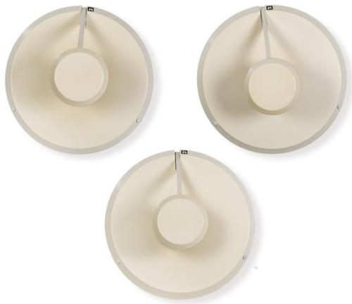  Conjunto de 3 apliques de pared con estructura metálica lacada en tono crema, compuesta por placa circular y cuerpo cilíndrico central unido por brazo recto. Sistema de iluminación indirecta proyectada sobre muro.