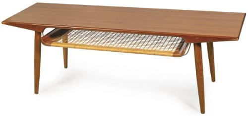  Mesa de centro con tapa rectangular sobre cuatro patas cónicas en madera de teca y estante inferior tejido. Estante inferior con tejido ortogonal en ratán natural o cuerda de papel trenzada.