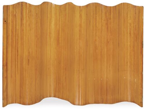  Biombo de cuerpo único ondulado, con estructura autoportante formada por panel curvo de madera laminada, con superficie exterior revestida en listones verticales de madera. Distintivo circular metálico del editor “Manufrance – Saint-Étienne” aplicado sobr