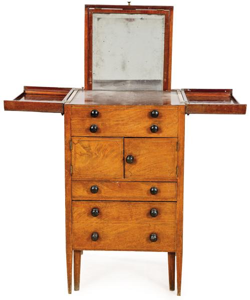  Mueble tocador Jorge III de madera de caoba, con tapa abatible, compartimentos y cajones; tiradores torneados y ebonizados.