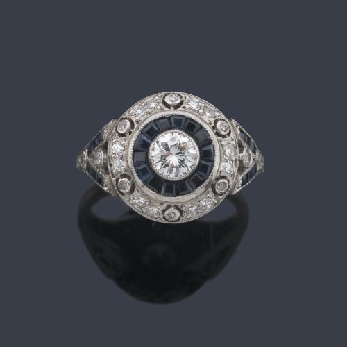  Anillo con diseño de 'ojo de perdiz' con brillante central de aprox. 0,35 ct con orla de zafiros de aprox. 0,90 ct en total y brillantes de aprox. 0,36 ct.