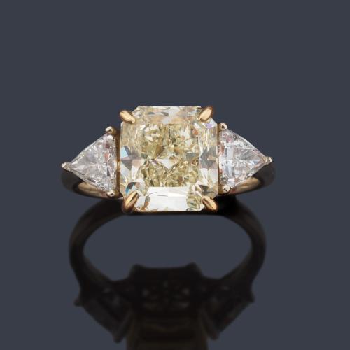 Anillo con diamante 'fancy light yellow' de aprox. 4,45 ct con dos diamantes talla triángulo de aprox. 0,80 ct en total. Certificado GIA.