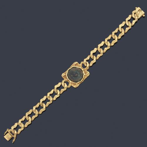  Pulsera con moneda antigua romana el centro en montura de eslabones barbados en oro amarillo de 18K.