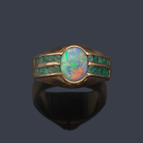 Anillo con ópalo negro talla cabujón con dos bandas de esmeraldas talla redonda en ambos lados.