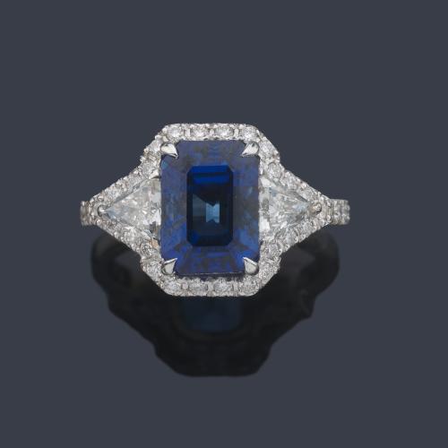  Anillo con zafiro central de aprox. 3,88 ct con dos diamantes talla triángulo de aprox. 0,63 ct y orla de brillantes de aprox. 0,95 ct en total.