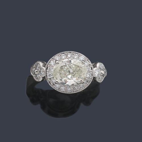  Anillo con diamante talla oval de aprox. 1,50 ct con orla y brazos con brillantitos de aprox. 0,46 ct en total.