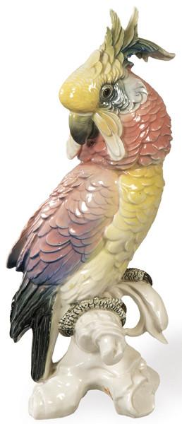 Figura de loro sobre rama de arbol en porcelana moldeada, pintada y esmaltada.