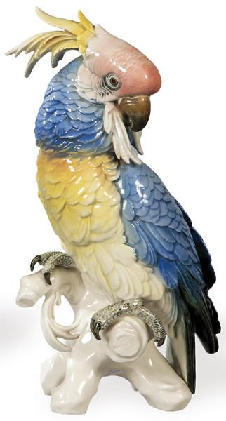 Figura de loro sobre rama de arbol en porcelana moldeada, pintada y esmaltada.