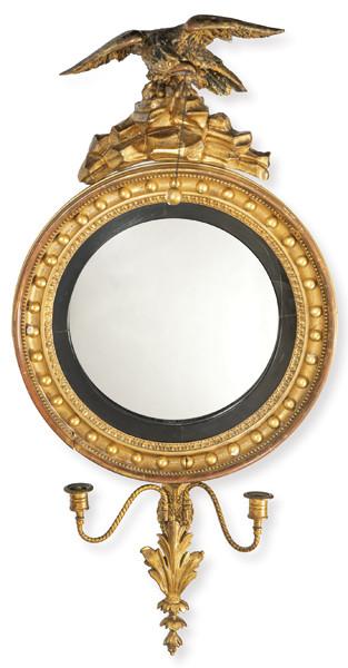  Marco Regencia de espejo convexo, con marco circular moldurado en madera tallada y dorada, rematado por una figura de aguila con alas extendidas en madera tallada. 