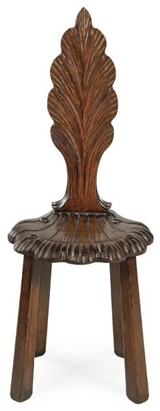 Silla “grotto” en madera tallada, con respaldo y asiento de perfil orgánico en forma de hoja y patas troncocónicas ahusadas.