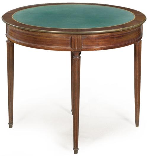  Mesa de juego estilo Directorio en madera de caoba, con tapa ovalada, que al abrirse se convierte en circular con tapete verde para jugar. Patas rectas acanaladas. S. XX