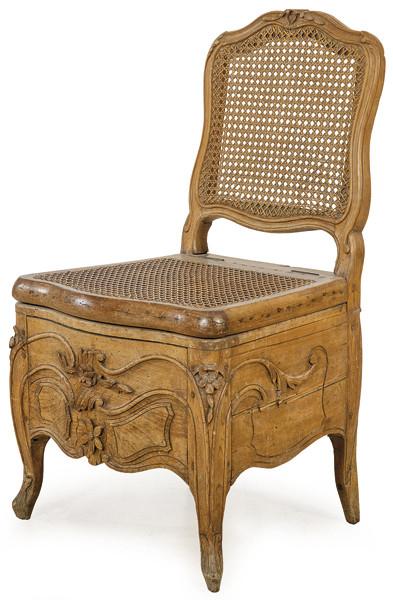 Silla Luis XV tipo aseo con tapa abatible, en madera de roble tallada en su color, con respaldo y asiento de rejilla.