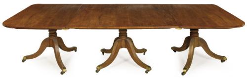  Mesa comedor extensible Jorge III, en madera de caoba sobre pedestales abalaustrados torneados apoyados en patas ligeramente cabriolé terminadas en ruedas.