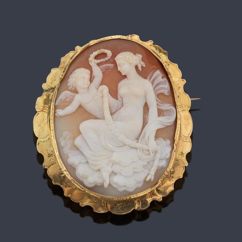  Broche camafeo con representación Mitológica de Afrodita y Cupido realizado sobre concha enmarcado en oro amarillo de 18K. Ppios S. XX.