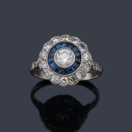  Anillo 'ojo de perdiz' con brillante central de aprox. 0,40 ct con doble orla de zafiros calibrados de aprox. 0,33 ct y brillantes de aprox. 0,87 ct en total.