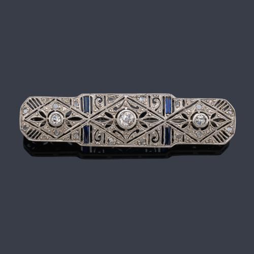  Broche - placa con diseño calado con tres diamantes talla antigua y rosa, con cuatro zafiros calibrados.