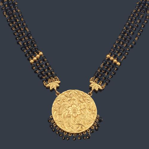 Collar largo 'Mangalsutra' con cuatro hilos de cuentas de ónix insertadas en hilo de oro amarillo con remate circular o 'wati' con motivo floral cincelado en oro amarillo de 21K.