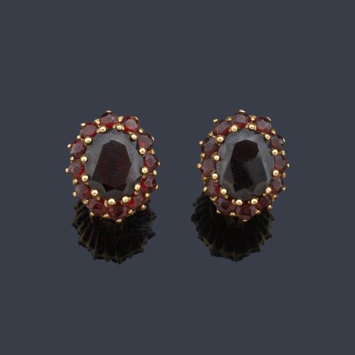 Pendientes cortos con pareja de granates talla oval en montura de oro amarillo de 18K.