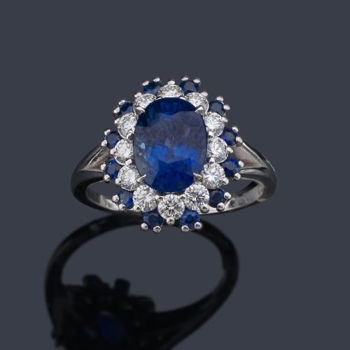  Anillo con zafiro talla oval de aprox. 2,95 ct con orla de brillantes de aprox. 0,60 ct y zafiros talla redonda de 0,37 ct en total.