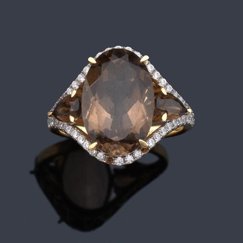  Anillo con cuarzo ahumado talla oval de aprox. 5,60 con orla de brillantes, en montura de oro amarillo de 18K y vista en oro blanco.