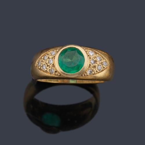 Anillo con esmeralda central talla redonda de aprox. 1,00 ct con brillantitos en ambos lados.