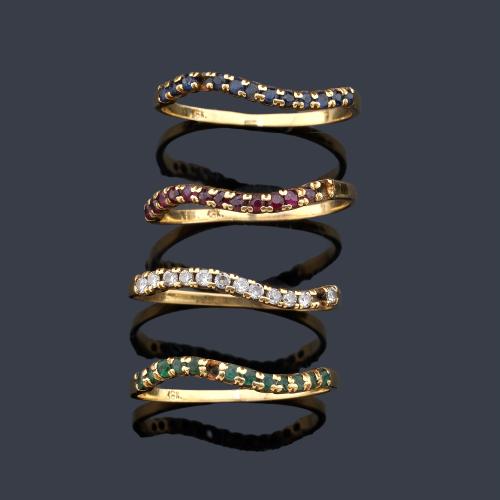 Cuatro anillos con banda de esmeraldas, brillantes, zafiros y rubíes en montura de oro amarillo de 18K.