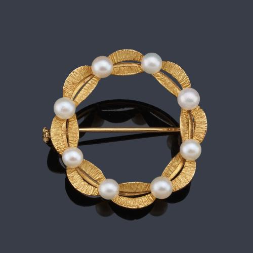 Broche circular con decoración de perlitas en montura de oro amarillo de 18K.