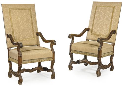 Pareja de butacas estilo Luis XIV en madera de nogal tallada, con apoyabrazos y patas delanteras terminadas en volutas y unidas por chambrana en "H"
