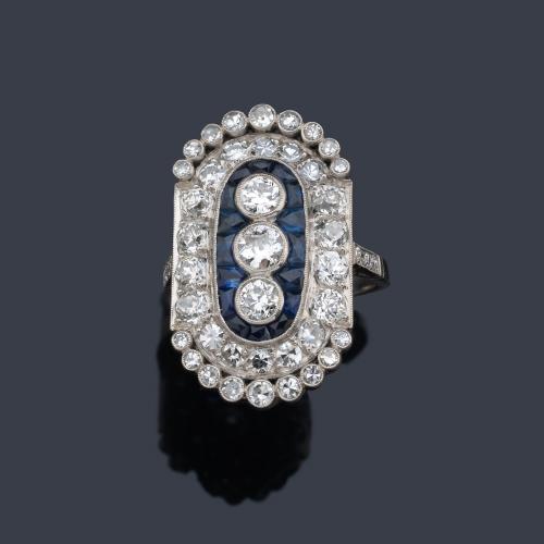  Anillo lanzadera con tres brillantes de mayor tamaño y orla de diamantes de aprox. 2,80 ct en total y zafiros calibrados de aprox. 4,42 ct.