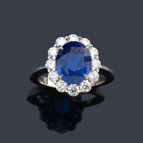  Anillo con gran zafiro talla oval de aprox. 4,98 ct con orla de brillantes de aprox. 1,05 ct en total. Certificado Bellerophon.