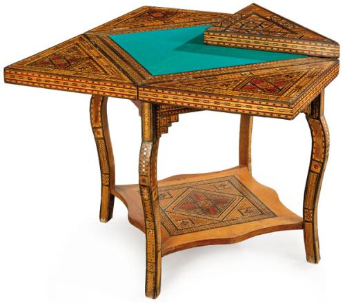  Mesa de juego con decoración de taracea granadina. Tapa desplegable tipo pañuelo, que al abrirse revela un interior con tapete para juego. Patas ligeramente curvas unidas por un estante en la parte inferior. España, h. 1900