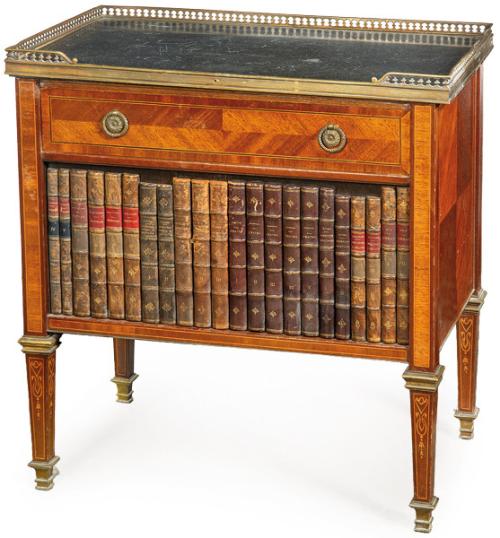  Mueble auxiliar estilo neoclásico en madera de caoba, con tapa de mármol negro y barandilla de latón calada, cajón y dos puertas abatibles simulando libros antiguos. S. XX