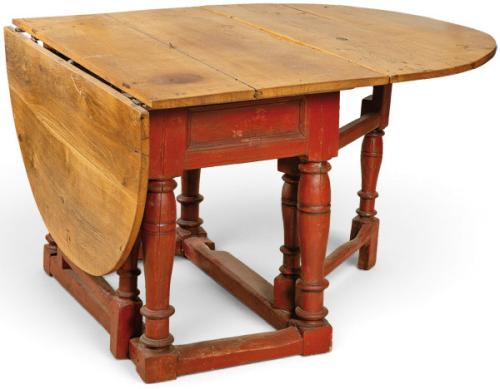  Mesa de comedor de alas semicirculares en madera de roble en su color, sobre estructura de patas torneadas unidas por chambranas rectos en madera pintado de rojo.