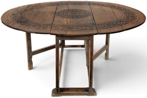  Mesa de comedor redonda de alas en madera de roble, con decoración tallada, sobre patas rectas.