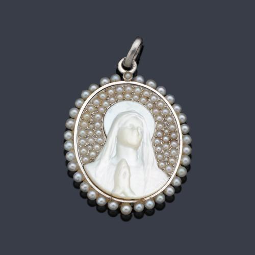  Medalla devocional época 'art decó' con La Imagen de La Virgen en nácar, con orlas de perlitas aljófar realizado en montura de platino. Año 1910.