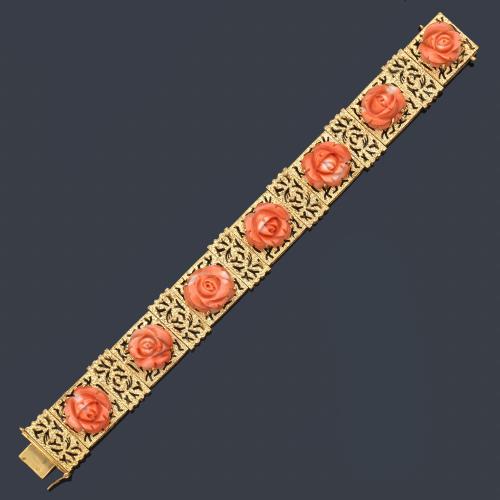  Pulsera con siete motivos florales tallados en coral sobre montura calada de oro mateado amarillo de 18K. Años '60.