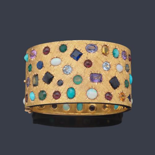  Pulsera ancha con turquesas, amatistas, zafiros, aguamarinas, rubíes, citrinos sobre montura cincelada en oro amarillo de 14K. Años '70.